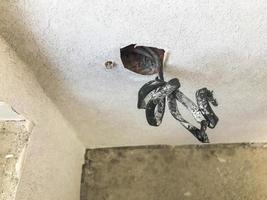 Open thick black bare wire with electricity protrudes from the bottom in the wall of the apartment during repair, construction photo