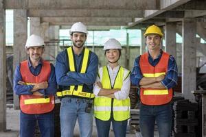 Portrait of experienced diversity team of engineer, architect, worker and safety manager smiling together at the construction site in safety vest and helmet photo