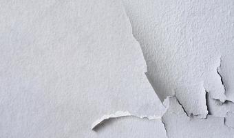 Cracked white color paint on cement wall background, Broken rough concrete surface photo