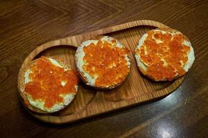 bocadillos con caviar rojo en una bandeja de madera. foto