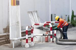 Engineer is transferring oil into tank, resting from oil tanker truck. photo