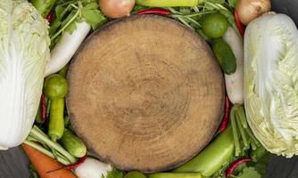 Top view wooden cutting board center with vegetables around photo