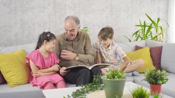 Grandfather shows his grandchildren the picture album. Grandparents and grandchildren looking at old pictures are happy and sympathetic. video