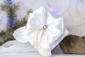 A Christmas gift decorated with a beautiful bow on a light background with a fir twig. Gifts, joy, surprise. Selective focus. the concept of Christmas and New Year. photo