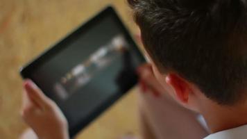 Teen browsing photos on tablet computer by the table video