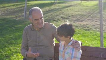 abuelo nieto charlando al aire libre. anciano charlando con su nieto en el parque.