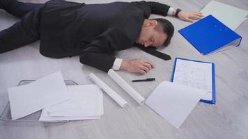 Businessman fainting. The businessman, who has fallen to the ground with the documents in his hand, lies unconscious on the floor. video