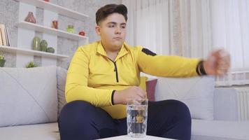Diet boy. Overweight problem. A child on a diet waits for his hour to drink water. He looks at his watch and drinks his water. video