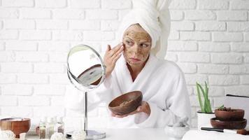 soins de beauté du visage. portrait d'une jeune femme séduisante mettant un gommage au café sur la peau du visage. femme appliquant un gommage pour le visage video