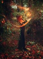 Adorable young redhair lady wizard conjures in the forest photo