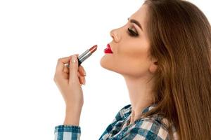 Profile portrait of young beautiful girl with lipstick in hand photo