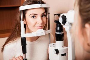 Lovely Young adult woman is having eye exam performed by eye doctor photo