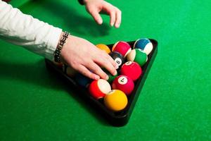 male hands to place the balls in the triangle to play eight ball  at pool table photo