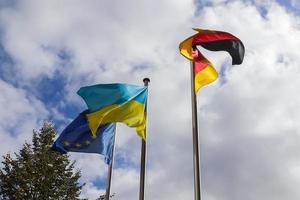 las banderas de ucrania, alemania y la unión europea vuelan una al lado de la otra contra el cielo azul. foto