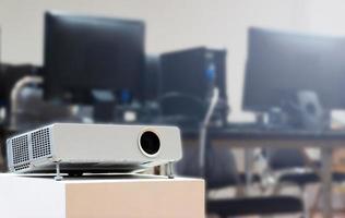 Close up projector with computer desktop on table background in computer classroom photo