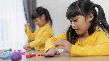 The little girl is learning to use colorful play dough in a room photo