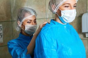 asistente médico la ayuda a prepararse para la cirugía
