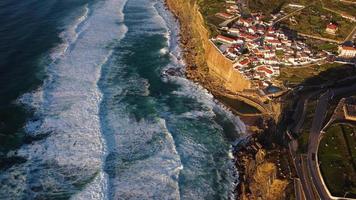 vue aérienne par drone d'une piscine naturelle dans l'océan, à côté de la falaise et d'un village balnéaire au coucher du soleil. azenhas do mar, portugal. meilleures destinations du monde. endroits les plus visités. vacances. video