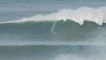surfer is rijden een reusachtig groot Golf in nazare, Portugal. grootste golven in de wereld. toeristisch bestemming voor surfing en geliefden van radicaal sport. Jet skis in de water. verbazingwekkend bestemmingen. video