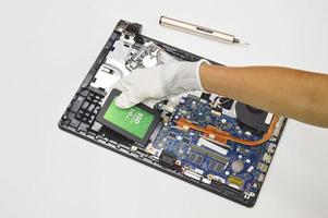 Photograph of a technician inserting a 240 GB ssd hard drive on a laptop motherboard on a white background. photo