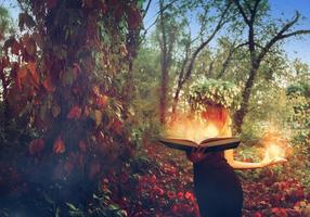 young redhead stunning witch reads magic book in the forest