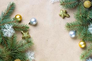 border of fir tree branch with gold decoration on craft paper for christmas card with copy space for text. photo