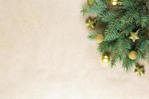 corner of fir tree branch with gold decoration on craft paper for christmas card with copy space for text. photo
