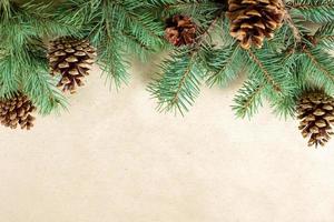Border of fir tree branch with cones on craft paper for christmas card with copy space for text. Top view, flat lay photo