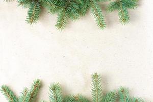 border of fir tree branch on craft paper for christmas card with copy space for text. Top view, flat lay photo