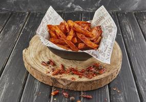 Sweet potato fried in oil with pepper on wooden board, serving in cafe photo