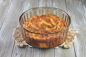 Puffed cauliflower souffle in transparent bowl on wooden background photo