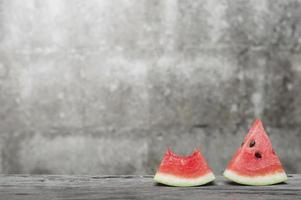 Fresh watermelon slice on wooden table with old brick wall background photo