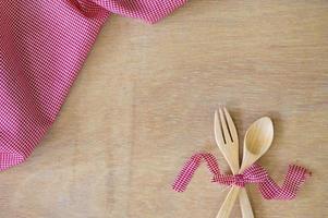 utensilios de cocina. tenedor y cuchara de madera con tela roja sobre fondo de madera foto