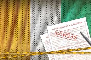 Ivory Coast flag and Health insurance claim form with covid-19 stamp. Coronavirus or 2019-nCov virus concept photo