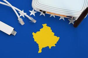Kosovo flag depicted on table with internet rj45 cable, wireless usb wifi adapter and router. Internet connection concept photo