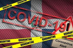 Dominican Republic flag and Covid-19 quarantine yellow tape with red stamp. Coronavirus or 2019-nCov virus photo