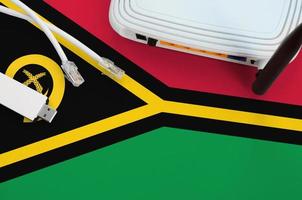 Vanuatu flag depicted on table with internet rj45 cable, wireless usb wifi adapter and router. Internet connection concept photo
