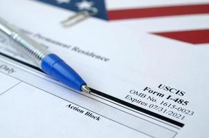 I-485 Application to register permanent residence or adjust status blank form lies on United States flag with blue pen from Department of Homeland Security photo