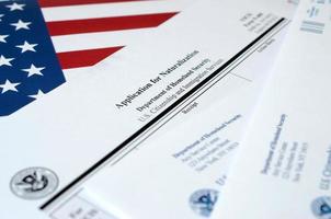 N-400 Application for Naturalization blank form lies on United States flag with envelope from Department of Homeland Security photo