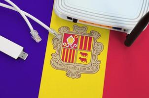 Andorra flag depicted on table with internet rj45 cable, wireless usb wifi adapter and router. Internet connection concept photo