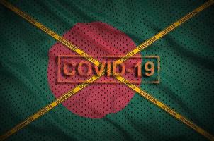 Bangladesh flag and Covid-19 stamp with orange quarantine border tape cross. Coronavirus or 2019-nCov virus concept photo