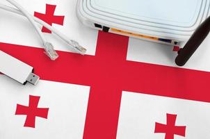Georgia flag depicted on table with internet rj45 cable, wireless usb wifi adapter and router. Internet connection concept photo