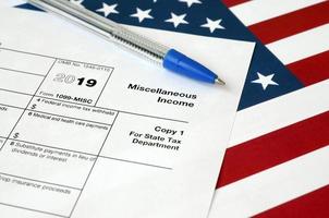 Form 1099-misc Miscellaneous income and blue pen on United States flag. Internal revenue service tax form photo