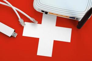 Switzerland flag depicted on table with internet rj45 cable, wireless usb wifi adapter and router. Internet connection concept photo