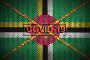 Dominica flag and Covid-19 stamp with orange quarantine border tape cross. Coronavirus or 2019-nCov virus concept photo