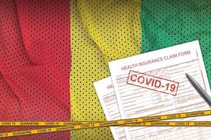 Guinea flag and Health insurance claim form with covid-19 stamp. Coronavirus or 2019-nCov virus concept photo