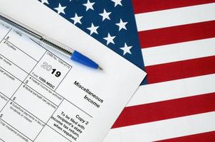 Form 1099-misc Miscellaneous income and blue pen on United States flag. Internal revenue service tax form photo