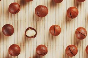 Flat composition with Australian macadamia nuts on bamboo light background. Patterns, repetitions photo