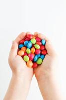 Multicolored candies in the hands of a child on a white isolated background photo