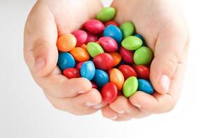 Multicolored candies in the hands of a child on a white isolated background photo
